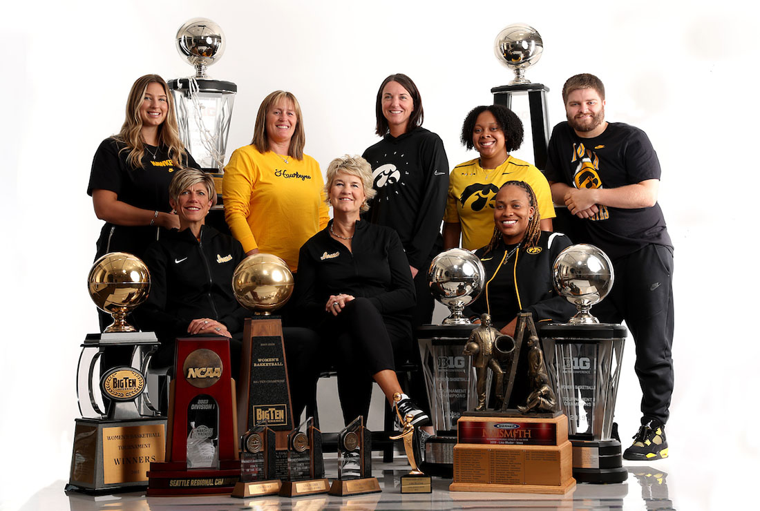 A group of people stand and sit among many trophies