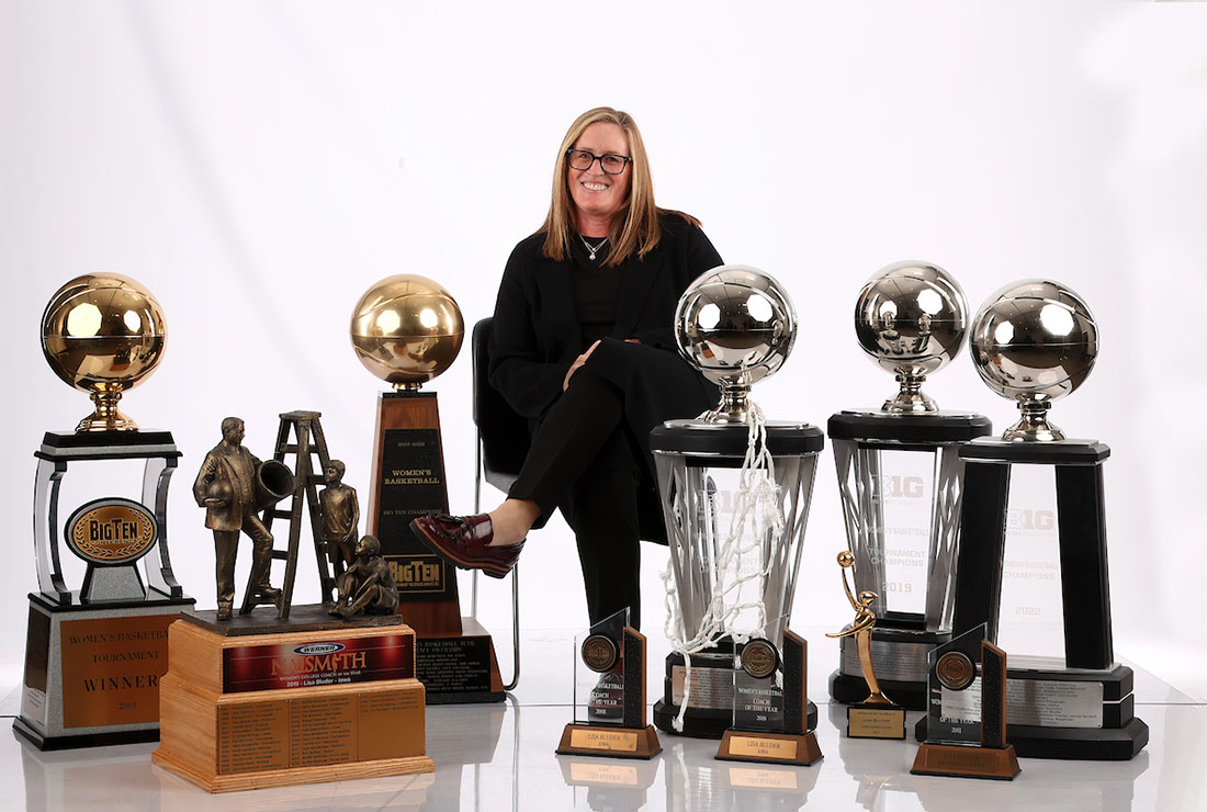 A woman sits surrounded by trophies