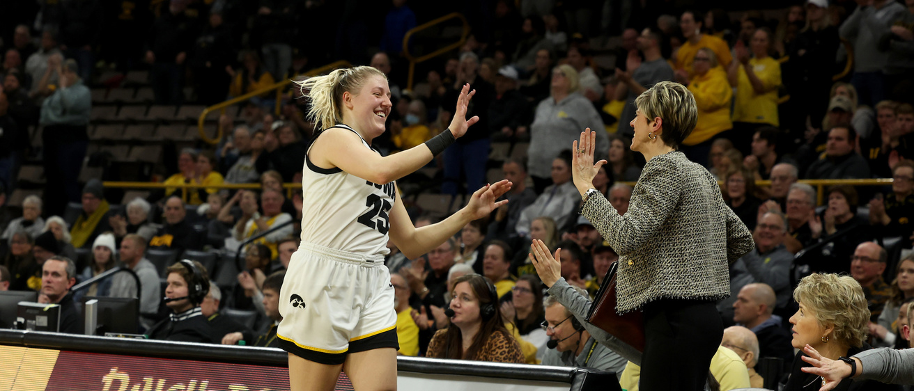 A women's basketball player high fives her coach